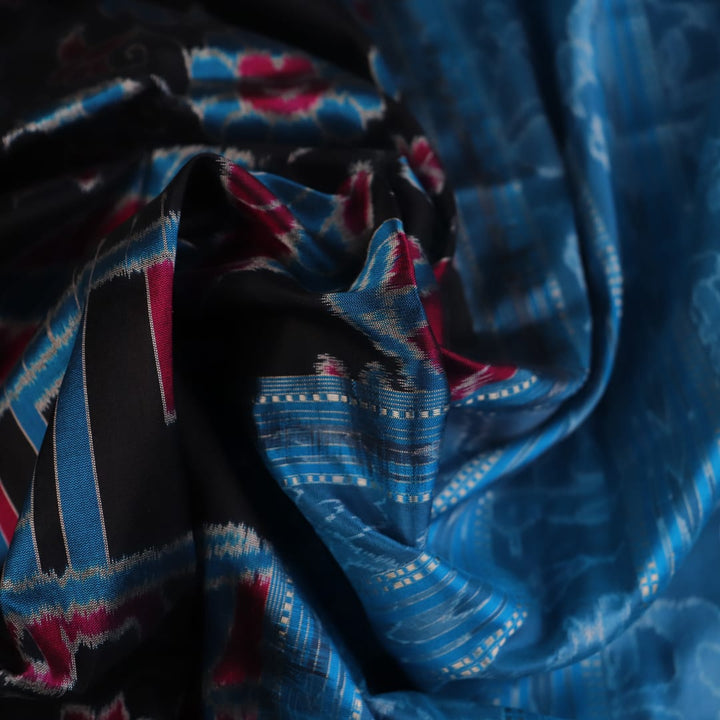 Close-up of black Sambalpuri silk saree fabric texture, showcasing the weave and subtle motif details.