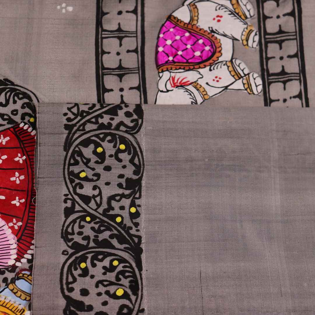 Close-up of grey silk Patachitra saree fabric showing hand-painted texture and intricate weave detail.