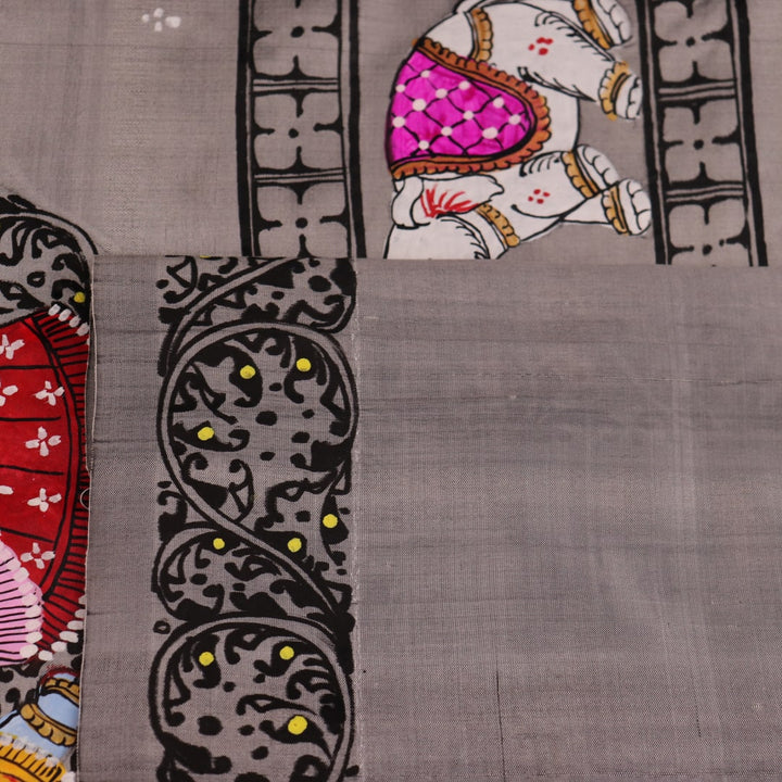Close-up of grey silk Patachitra saree fabric showing hand-painted texture and intricate weave detail.