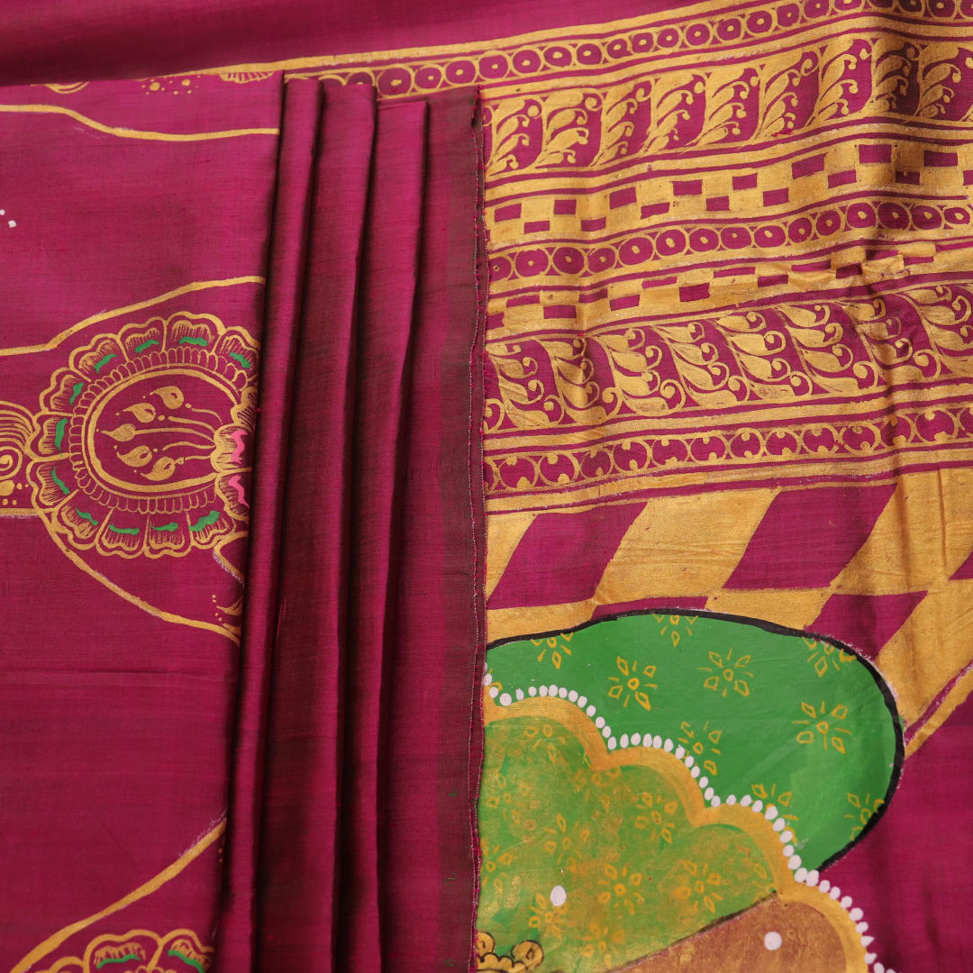 Close-up of magenta Patachitra silk saree fabric texture showing handloom weave and paint details.