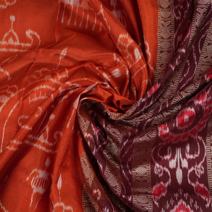 Extreme close-up of the lustrous rust Sambalpuri silk fabric, showing its fine weave and subtle motif texture.