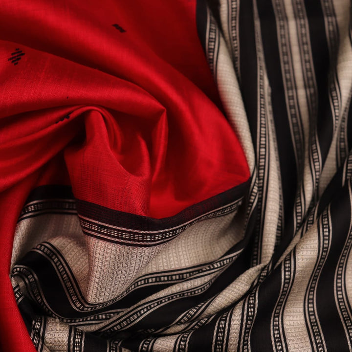 Close-up of the red and black plain silk fabric texture of a Berhampuri saree