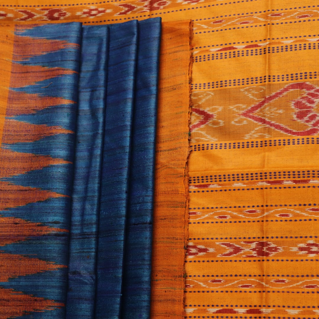 Close-up showcasing the intricate blue tussar silk fabric with a plain pattern and yellow accent hues.