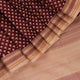 Close-up of maroon Tussar silk saree fabric, showing natural slub texture and printed pattern.