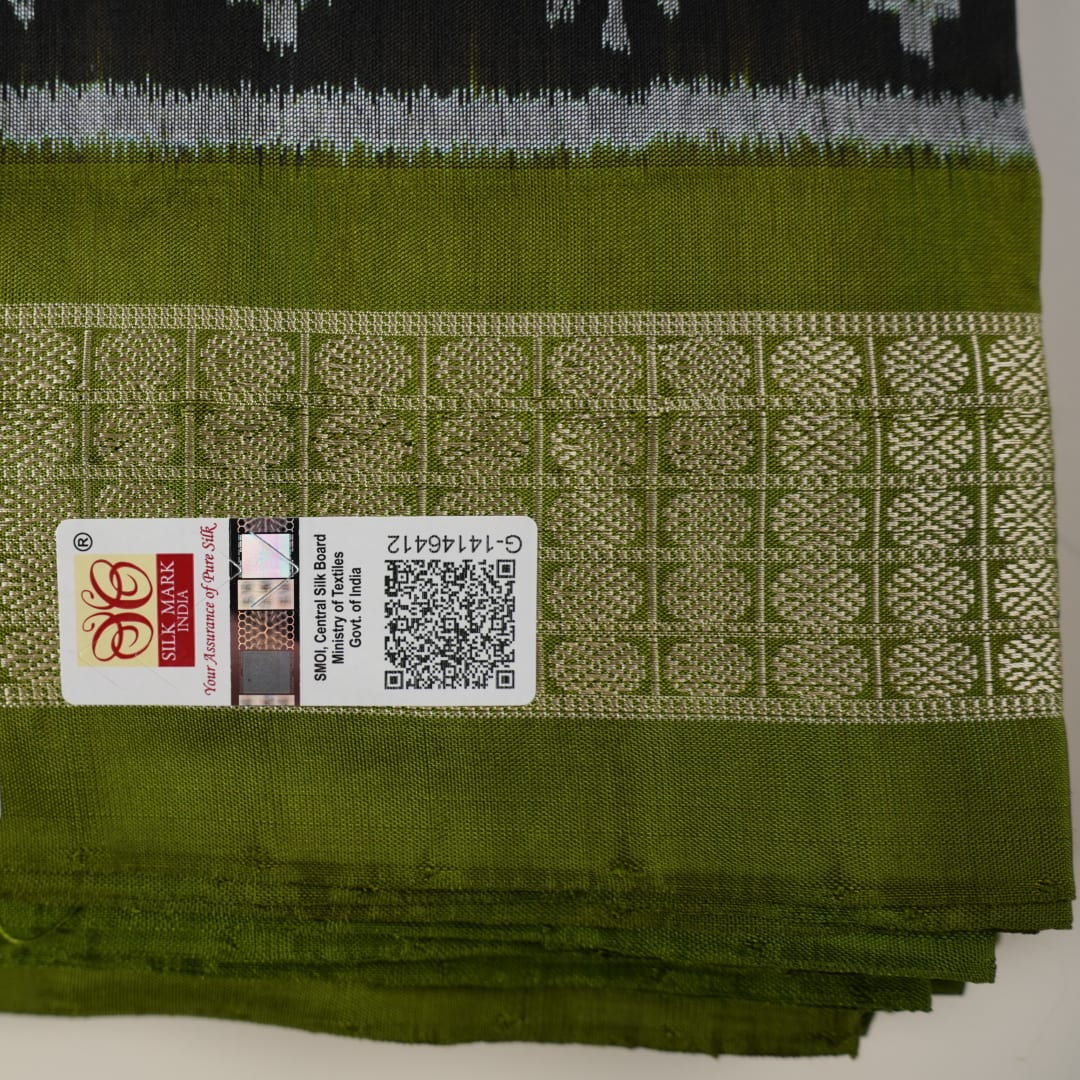 Close-up of the luxurious black and green Sambalpuri silk fabric texture and weave.