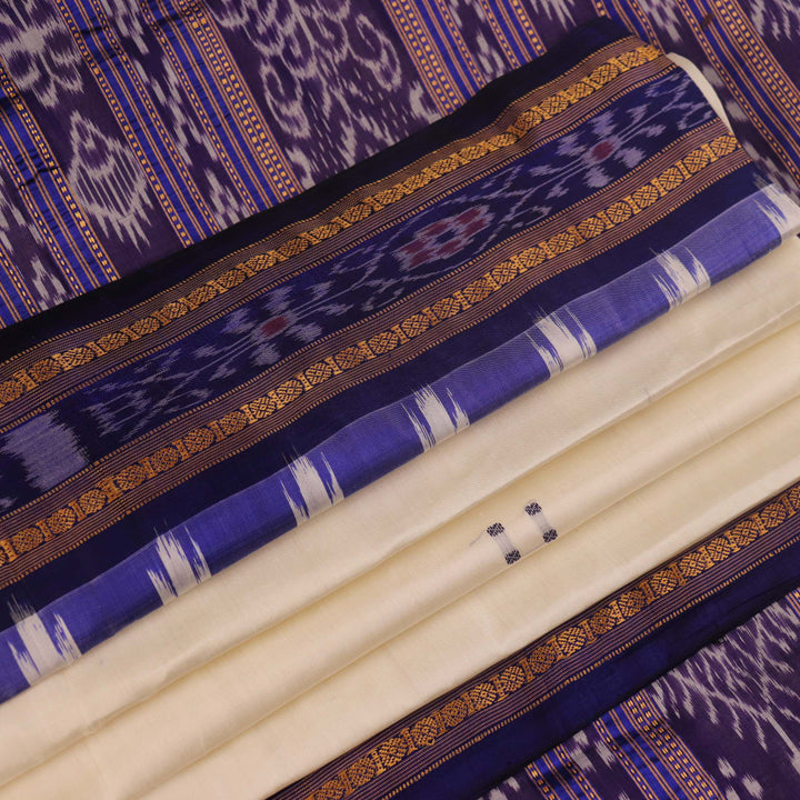 Woman elegantly draped in a white and blue Khandua silk saree with butta pattern.