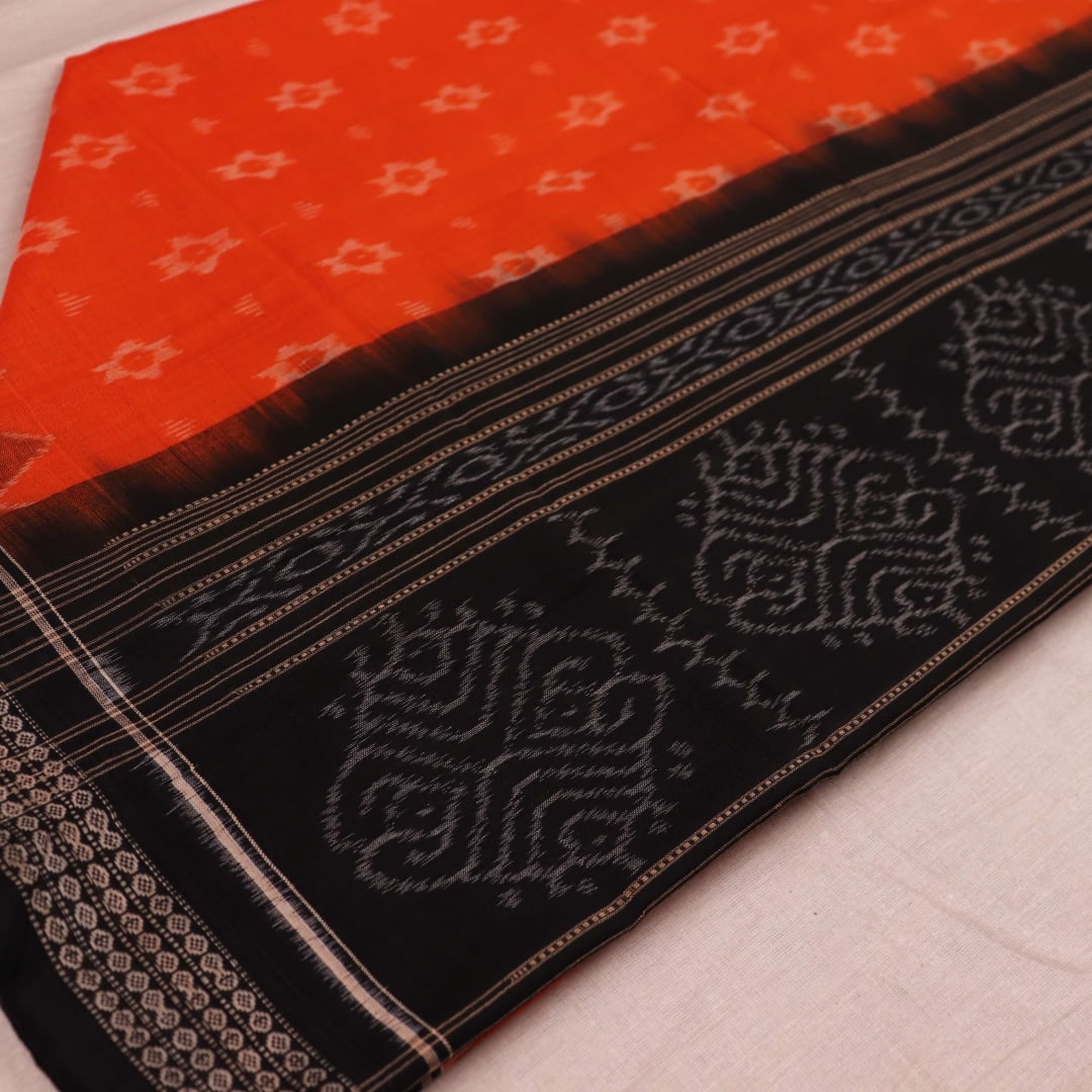 Full body view of a folded Sambalpuri cotton dupatta in orange with bold black motifs.