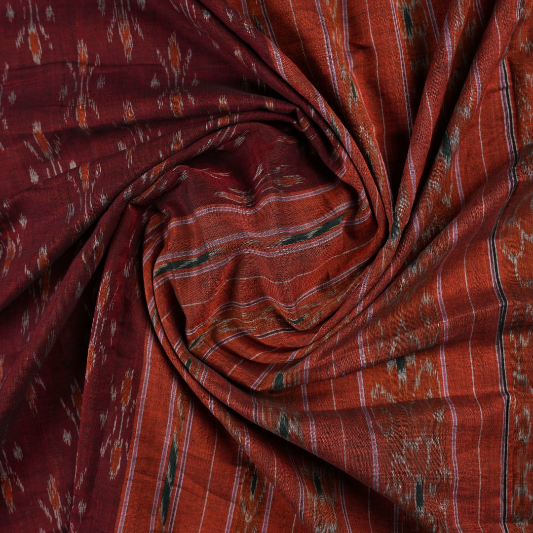 Model draped in a maroon and orange Sambalpuri cotton saree showcasing traditional handloom motifs.