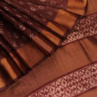 Close-up of the brown Tussar silk saree fabric, highlighting its natural slub texture and printed pattern.