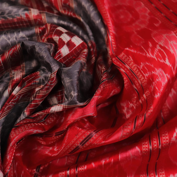 Close-up of grey Sambalpuri silk saree fabric showing intricate woven motifs and texture.