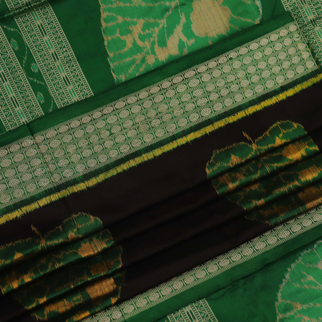 Close-up of the finely textured silk fabric in black, adorned with intricate Sambalpuri motifs in green