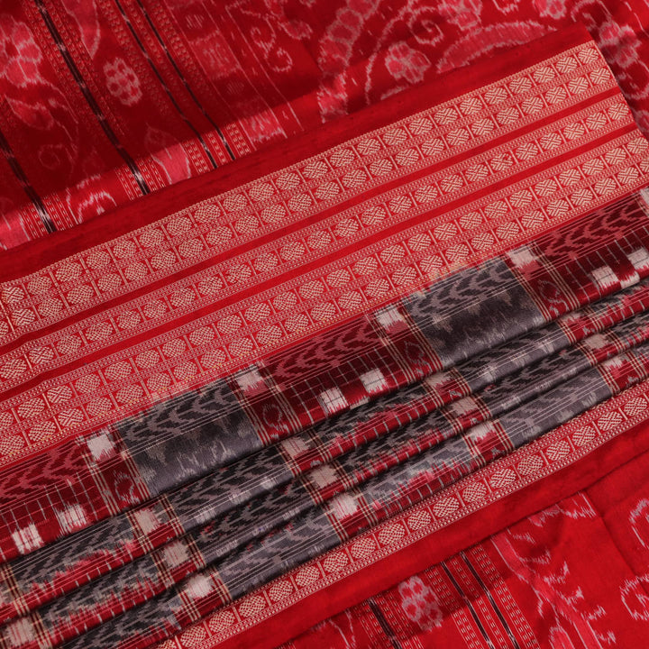 Close-up of grey Sambalpuri silk saree fabric showing intricate woven motifs and texture.