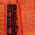 Close-up of maroon and orange Sambalpuri silk saree fabric texture, showcasing handloom weave and motif details.