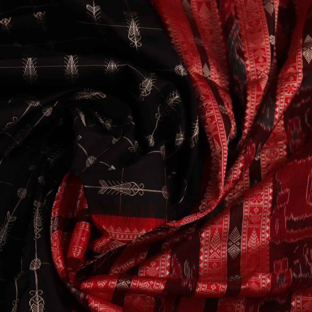 Close-up of black and red silk fabric texture with butta pattern.