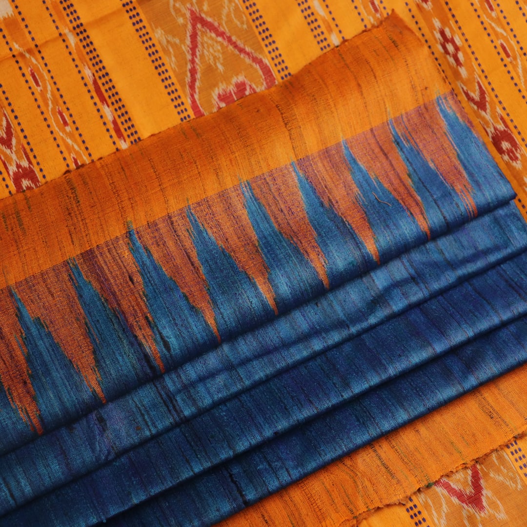 Close-up showcasing the intricate blue tussar silk fabric with a plain pattern and yellow accent hues.