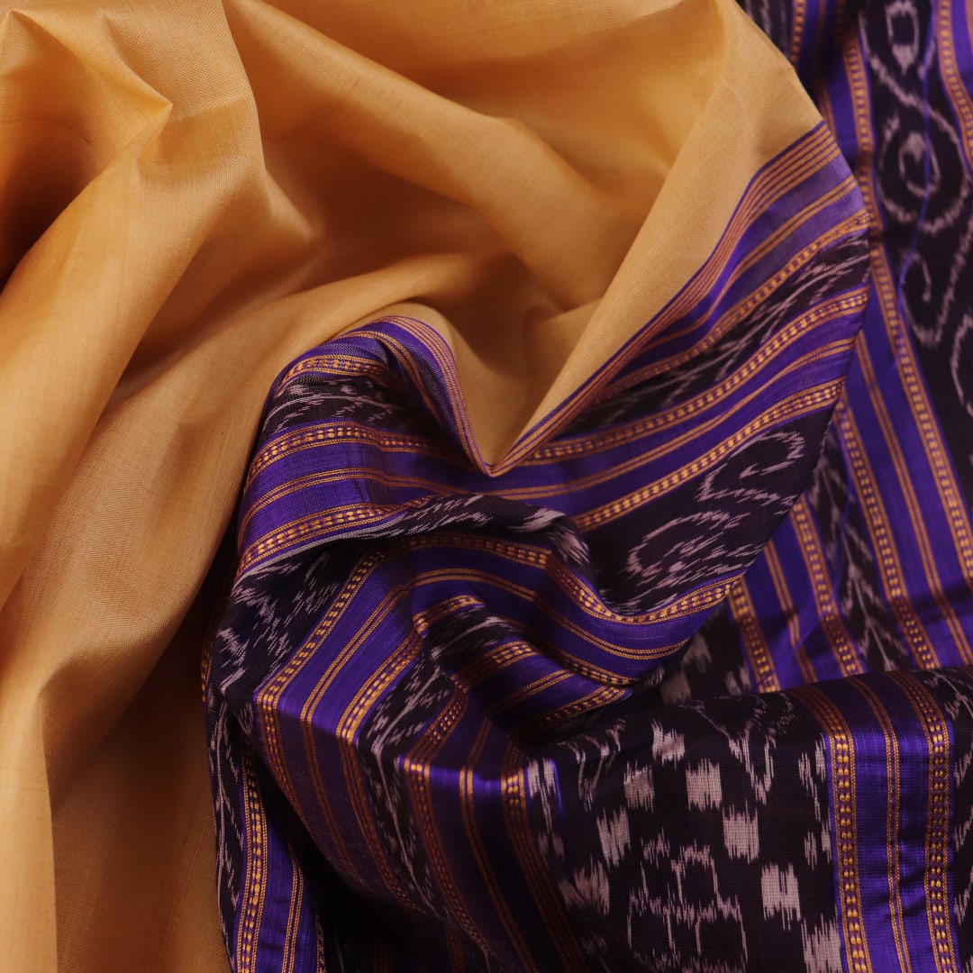 Woman draped in a cream and blue Khandua silk saree with butta pattern, showcasing the elegant drape and styling.