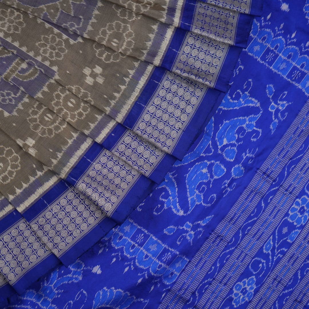Extreme close-up of the grey and blue Sambalpuri silk saree fabric, revealing its rich texture and intricate weave.