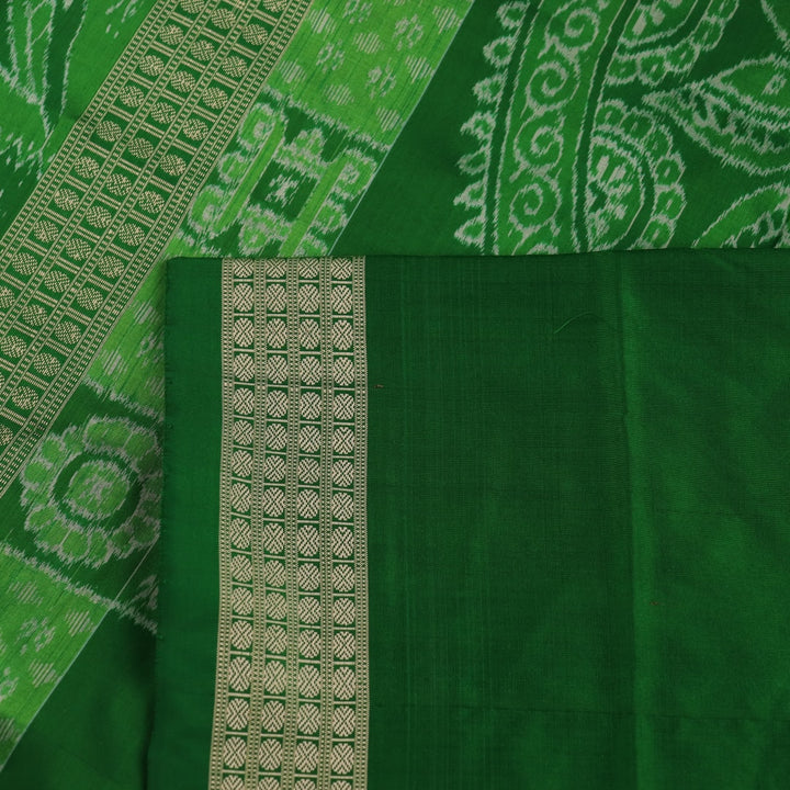 Close-up view of the intricate silk fabric texture of a green Sambalpuri silk saree with traditional motifs.