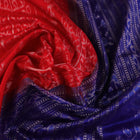 Close-up of red Sambalpuri silk saree fabric showing intricate woven motif texture and subtle blue threads.