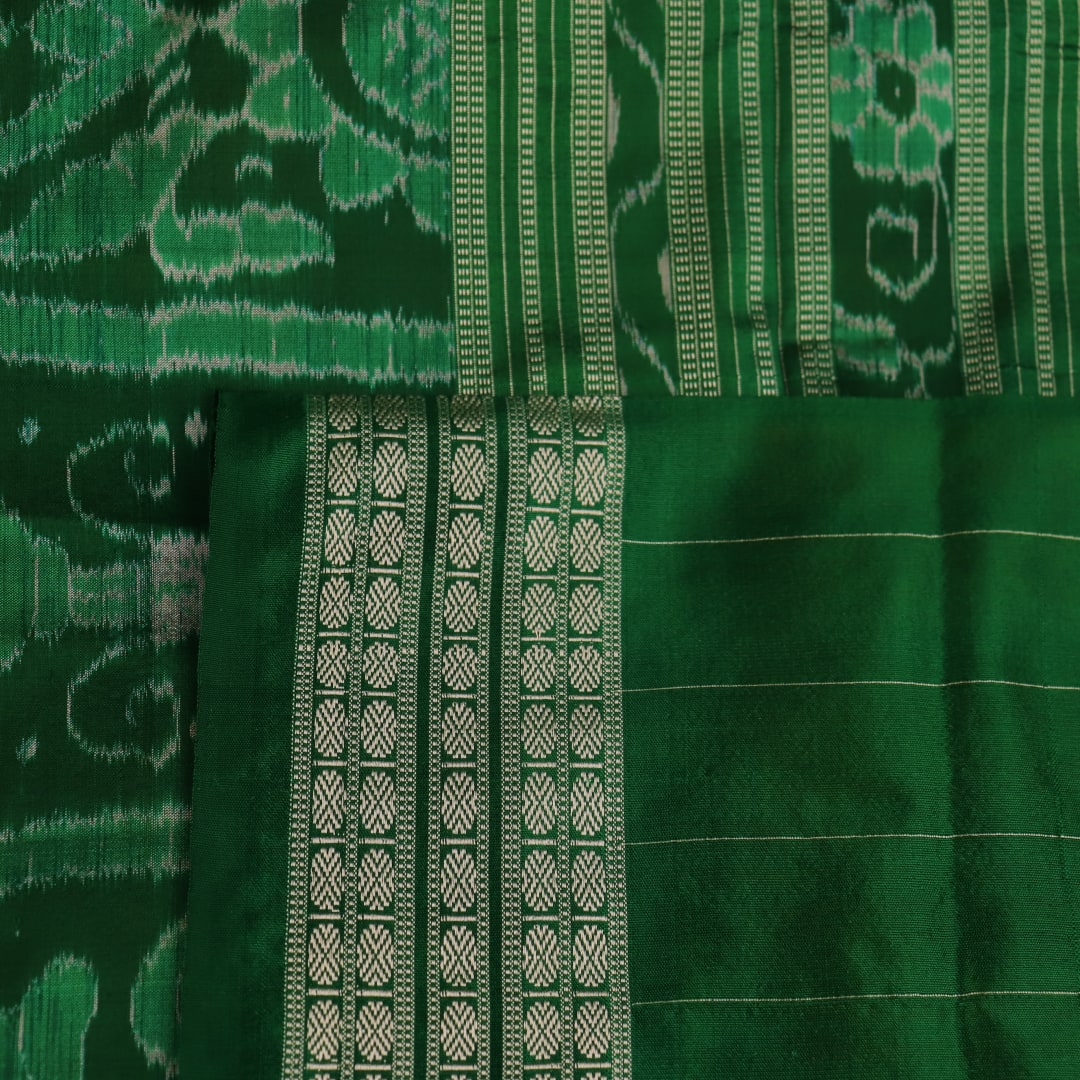 Close-up of yellow Sambalpuri silk saree fabric showing intricate motifs and woven texture.