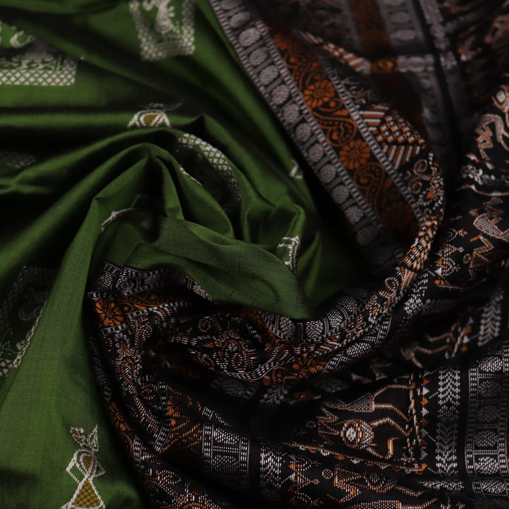 Close-up view of the silken texture of the Sambalpuri silk saree, showcasing green and black woven motifs.