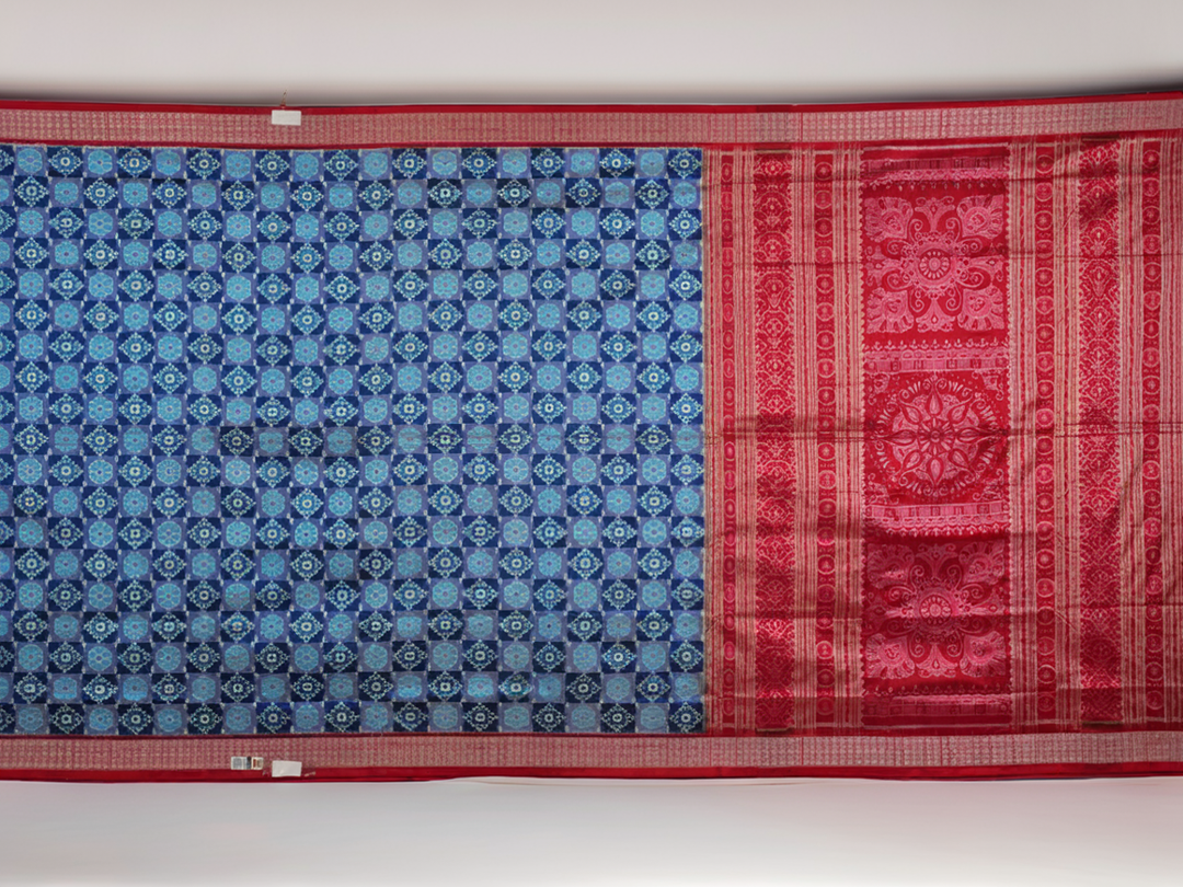 Close-up of the luxurious silk fabric texture and distinctive Sambalpuri ikat weave of the blue Pasapalli saree.
