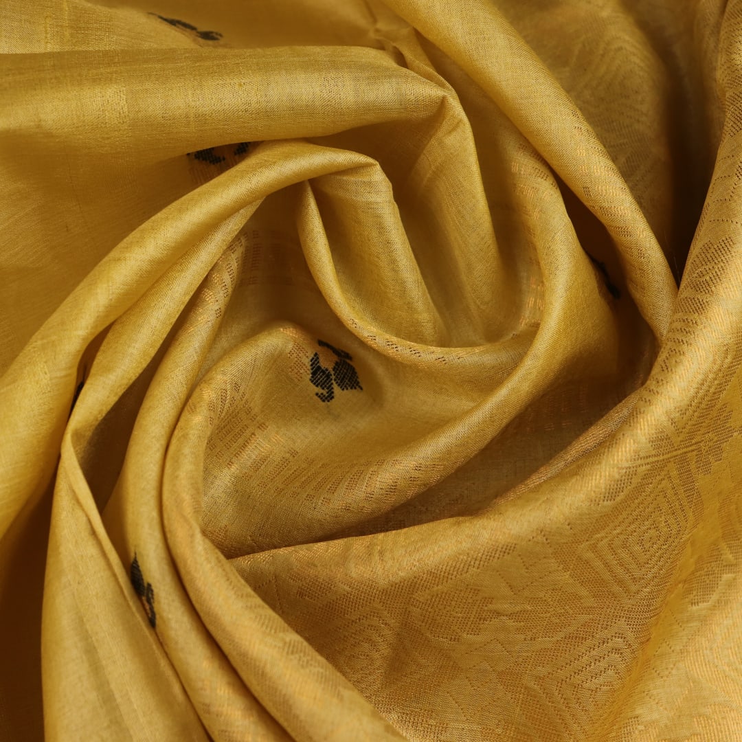 Close-up of yellow Tussar silk saree fabric with intricate butta patterns