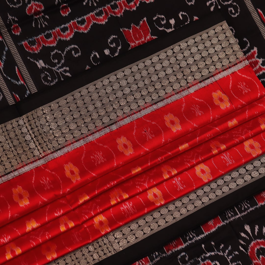 Close-up of red and black silk Sambalpuri saree fabric with intricate motifs