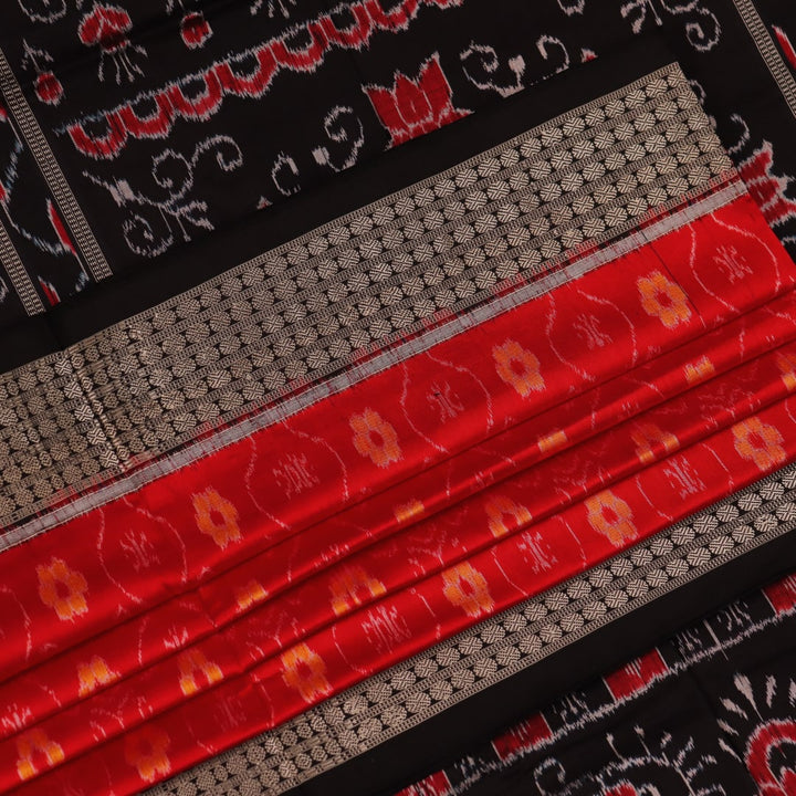 Close-up of red and black silk Sambalpuri saree fabric with intricate motifs