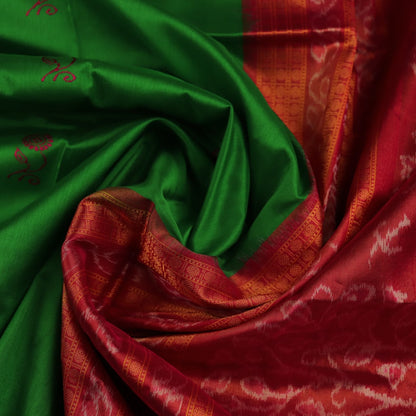 Close-up of luxurious green silk tissue saree fabric, showcasing intricate butta weaving details.