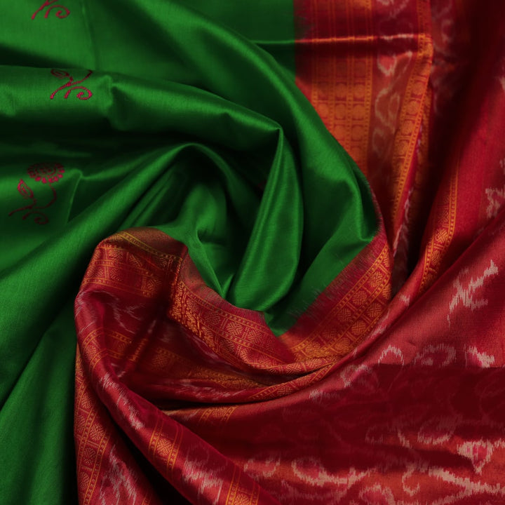 Close-up of luxurious green silk tissue saree fabric, showcasing intricate butta weaving details.