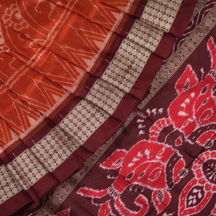 Extreme close-up of the lustrous rust Sambalpuri silk fabric, showing its fine weave and subtle motif texture.