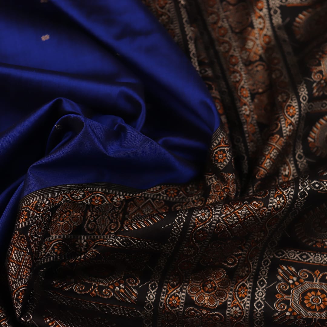 Close-up of the intricate woven texture of blue and black Bomkai silk saree with butta.