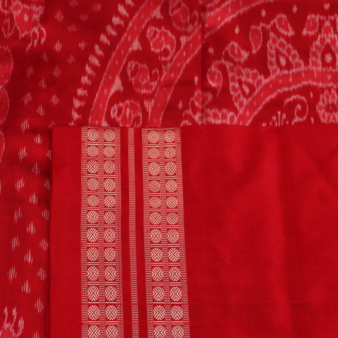 Close-up of grey and red Sambalpuri silk saree fabric showing intricate woven motif texture.