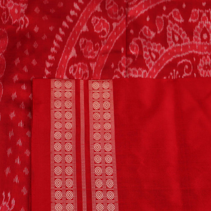 Close-up of grey and red Sambalpuri silk saree fabric showing intricate woven motif texture.