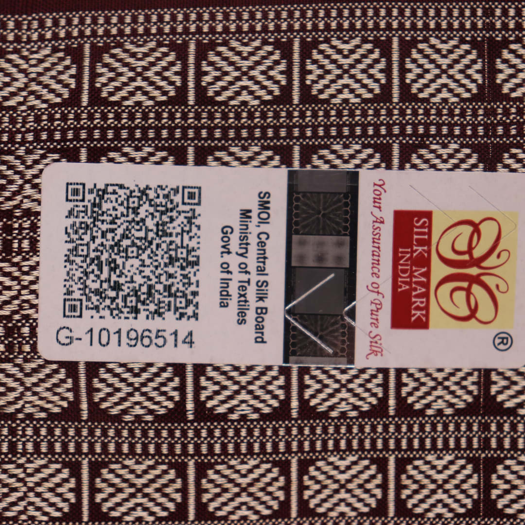 Close-up of peach and maroon Sambalpuri silk saree fabric showing intricate handloom texture and motifs.