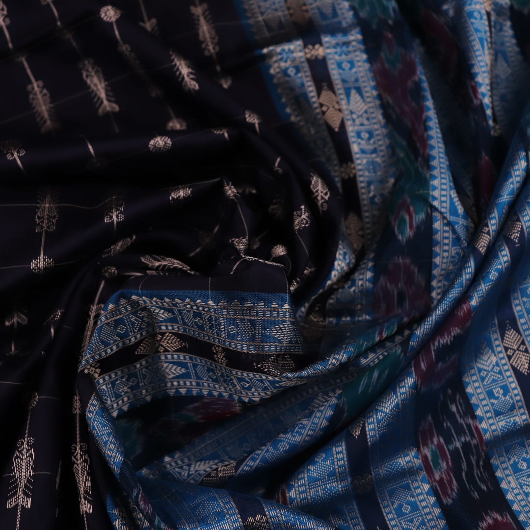 Close-up of handwoven Sambalpuri black silk saree fabric with intricate butta pattern