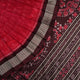 Ultra close-up of the red Sambalpuri silk saree fabric, revealing its luxurious texture and handloom weave.