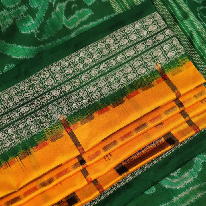 Close-up of yellow Sambalpuri silk saree fabric showing intricate motifs and woven texture.