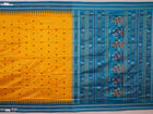 Close-up of the yellow Bomkai silk saree fabric texture, revealing its intricate weave and butta pattern.