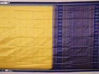 Textured close-up of yellow Bomkai silk saree fabric with blue butta pattern.