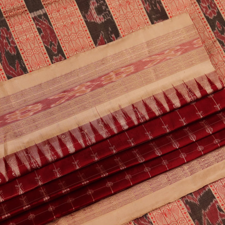 Close-up view of the richly textured silk fabric of a maroon and off-white Sambalpuri saree, featuring a delicate butta pattern.