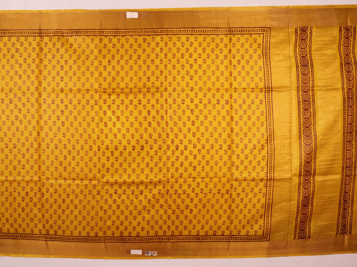 Close-up of the yellow printed Tussar silk saree's distinct slubby fabric texture.