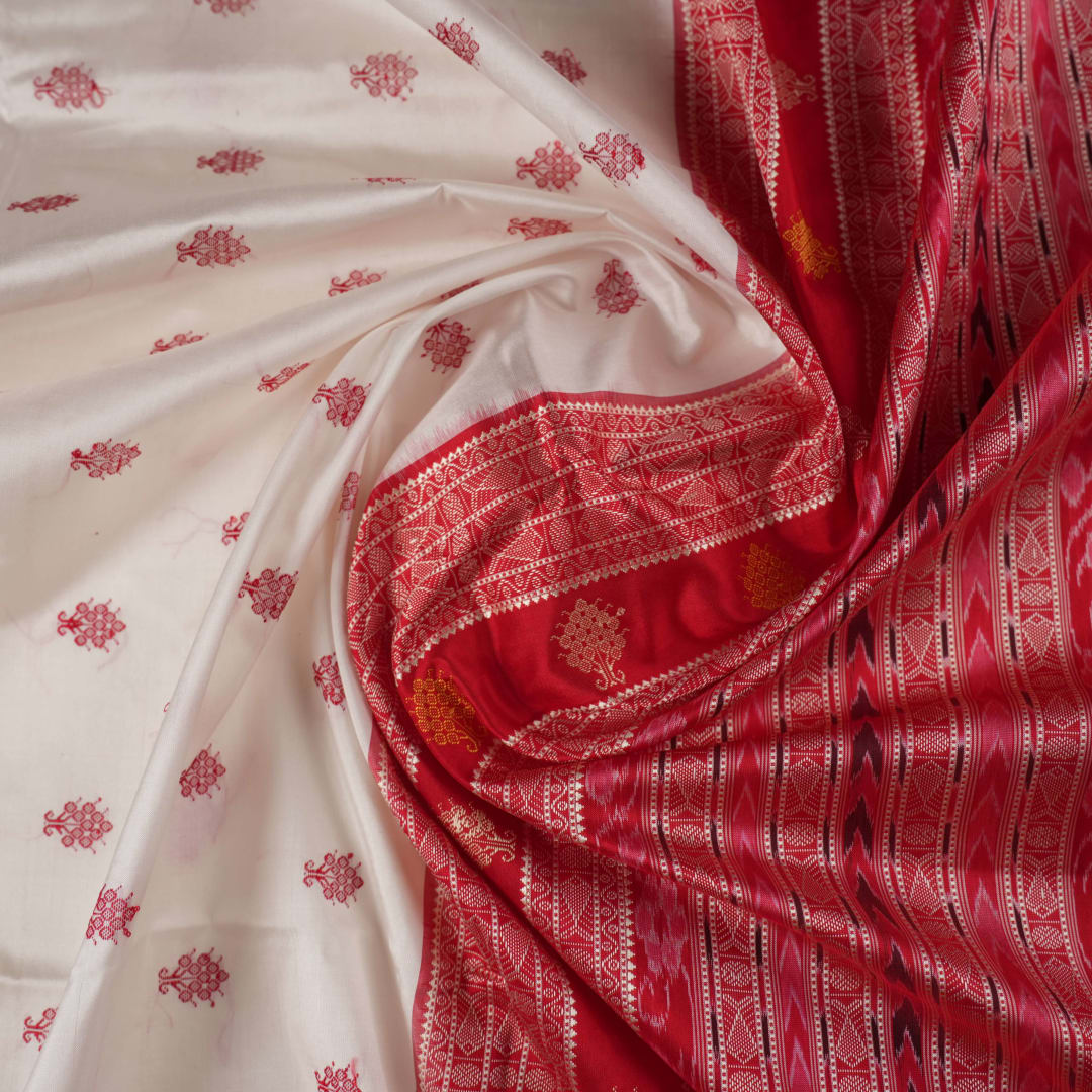 Extreme close-up revealing the rich Bomkai silk fabric texture and intricate handloom weave details in white and red.