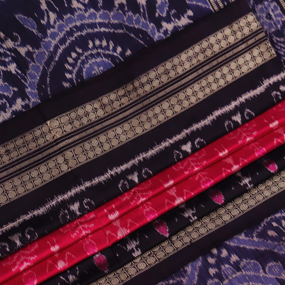 Close-up showing the intricate silk fabric texture of a magenta Sambalpuri saree with multicolor motifs.