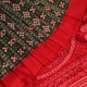 Close-up of green Sambalpuri silk saree fabric showing intricate woven motif texture and red thread details.