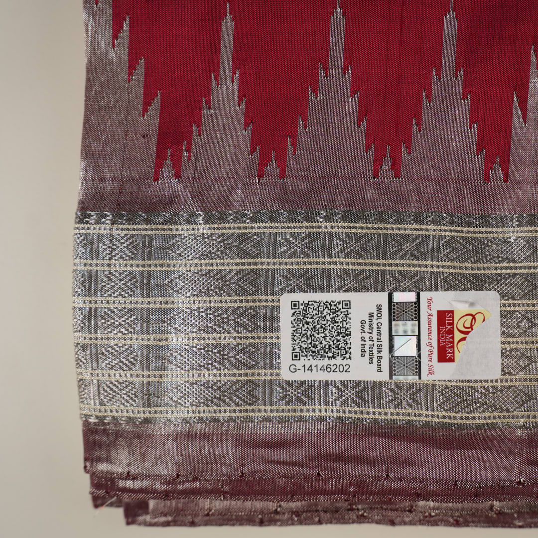Extreme close-up revealing the rich texture and intricate handloom weave of the maroon and grey Sambalpuri silk fabric.