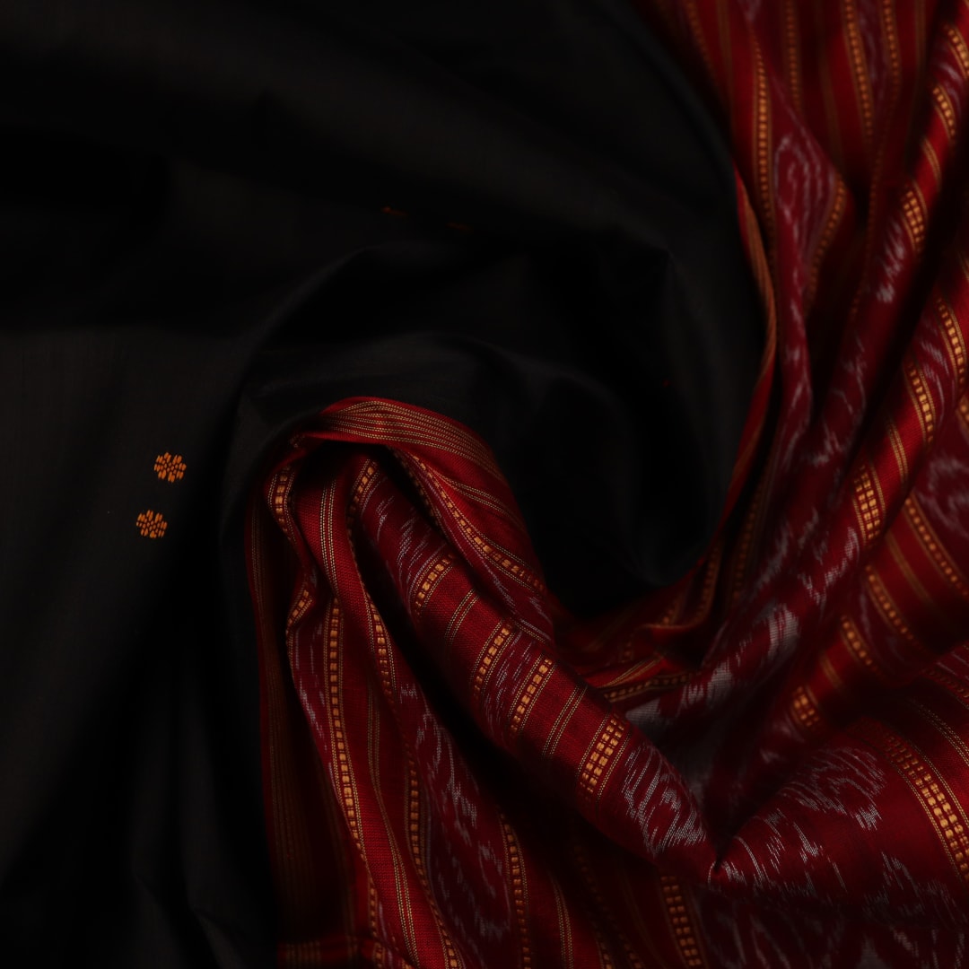 Draping view of a black Khandua silk saree with a red border and butta pattern