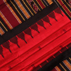 Textured close-up of red and black Sambalpuri Silk Saree fabric, highlighting the woven butta pattern.