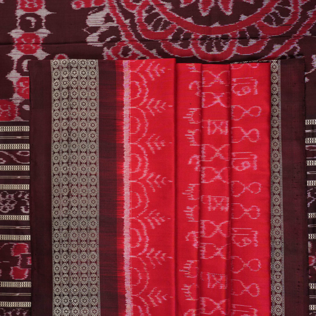 Ultra close-up of the red Sambalpuri silk saree fabric, revealing its luxurious texture and handloom weave.